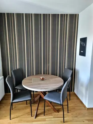 a table and chairs in a room with a striped wall at Apartman Court Prijedor in Prijedor