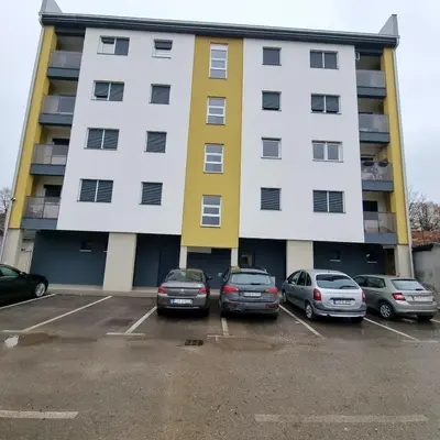 a large building with cars parked in a parking lot at Apartman Court Prijedor in Prijedor