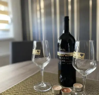 a bottle of wine and two wine glasses on a table at Apartman Court Prijedor in Prijedor