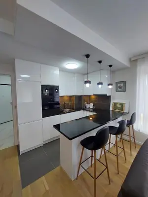 a kitchen with white cabinets and a black counter top at ELITE Park Lake in Tuzla