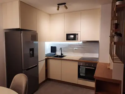 a kitchen with white cabinets and a black refrigerator at Apartman Stepe Stepanovica in Banja Luka