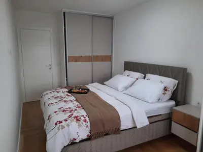 a bedroom with a large bed with white and red sheets at Apartman Stepe Stepanovica in Banja Luka