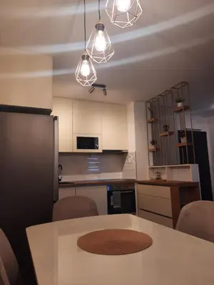 a kitchen with a table with chairs and lights at Apartman Stepe Stepanovica in Banja Luka