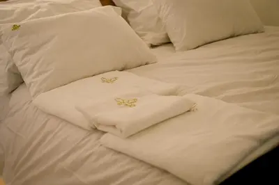 a bed with white sheets and pillows with gold crosses at Spa centar Doboj in Doboj