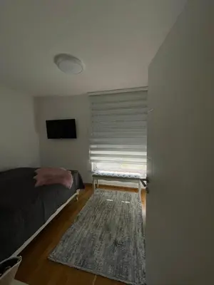 a bedroom with a bed and a window with a rug at Apartman Sisters in Sanski most