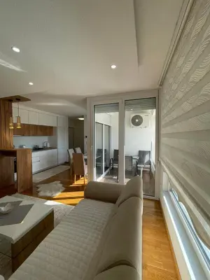 a living room with a couch and a kitchen at Apartman Sisters in Sanski most