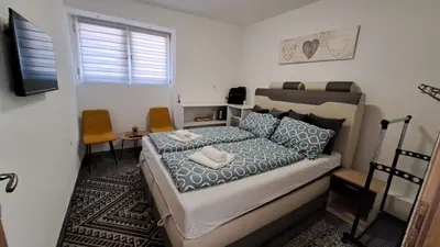 a small bedroom with a bed and two chairs at Elita Prenoćište in Bihać