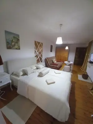 a bedroom with a large white bed and a living room at Apartman Dujaković in Banja Vrućica