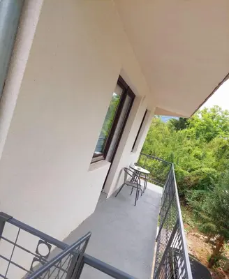 a balcony of a house with a table and a window at Apartman Emanuel in Jajce