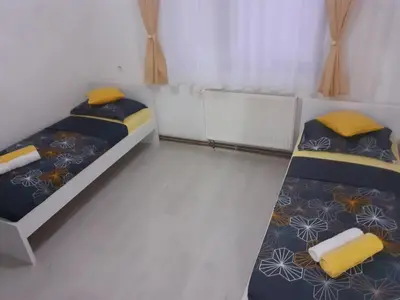 two beds in a small room with yellow pillows at Apartman Dalal - with access to river Una in Bihać