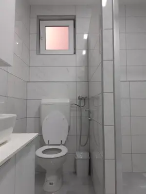 a white bathroom with a toilet and a window at Apartman Dalal - with access to river Una in Bihać