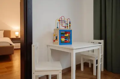 a small white table with chairs and a table with toys on it at Apartman Square Trg Prijedor in Prijedor
