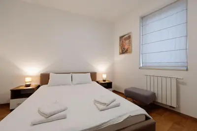 a bedroom with a large white bed and a window at Apartman Square Trg Prijedor in Prijedor