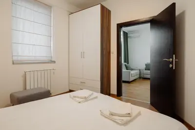 a bedroom with a white bed and a mirror at Apartman Square Trg Prijedor in Prijedor
