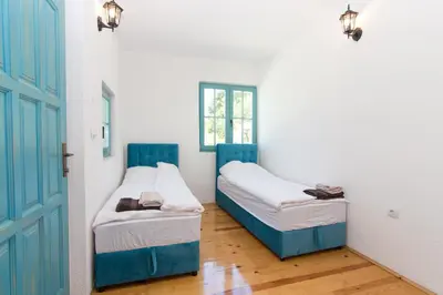 two beds in a room with a blue door at Retro Village Ravne in Visoko