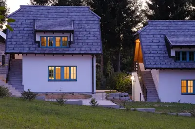 a house with a blue roof and yellow windows at Retro Village Ravne in Visoko
