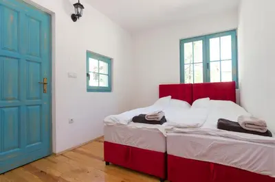 a bedroom with a red bed and a blue door at Retro Village Ravne in Visoko