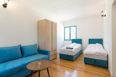 a living room with a blue couch and a bed at Retro Village Ravne in Visoko