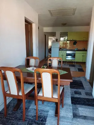a dining room with a table and chairs and a kitchen at Apartment EM 2 in Tuzla