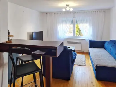 a living room with a blue couch and a desk at Kuća Mandić in Bosanska Gradiška