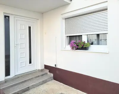 a white house with a window with a flower pot at Kuća Mandić in Bosanska Gradiška