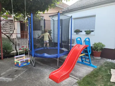 a child playing on a trampoline in a yard at Kuća Mandić in Bosanska Gradiška