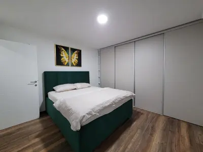 a bedroom with a green bed and white cabinets at Stan m&s, Boulevard-centar grada in Banja Luka