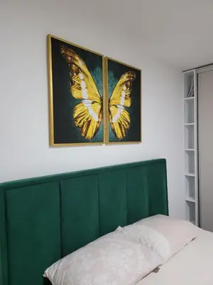 a green headboard with a butterfly picture on the wall at Stan m&s, Boulevard-centar grada in Banja Luka