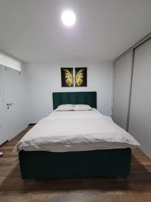 a bedroom with a large bed with a green headboard at Stan m&s, Boulevard-centar grada in Banja Luka