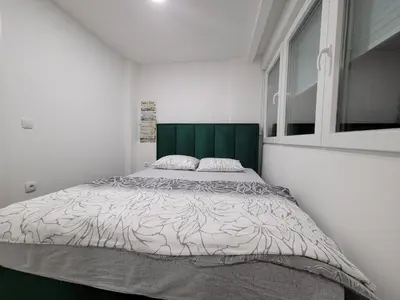 a bedroom with a large bed with a green headboard at Stan m&s, Boulevard-centar grada in Banja Luka