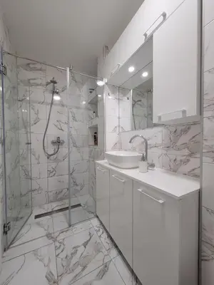 a white bathroom with a sink and a shower at Stan m&s, Boulevard-centar grada in Banja Luka