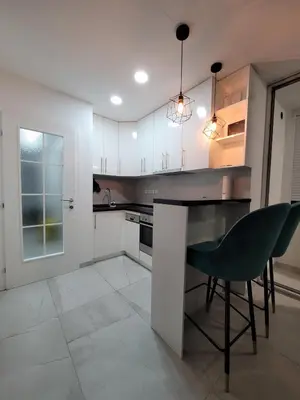 a kitchen with white cabinets and a green chair at Stan m&s, Boulevard-centar grada in Banja Luka