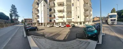 a building with cars parked in a parking lot at Valley of Pyramids Residence in Visoko