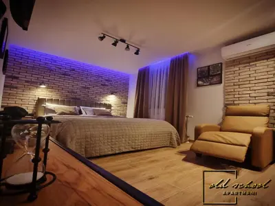 a bedroom with a large bed and a chair at Old School Apartments in Banja Luka
