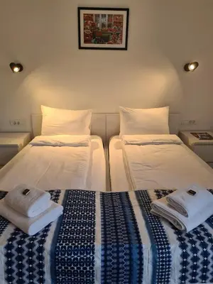two beds in a room with towels on them at Pansion Hukić B&B in Tuzla