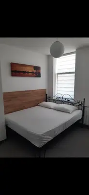 a bedroom with a large bed with a wooden headboard at Apartmani Aurora in Tuzla