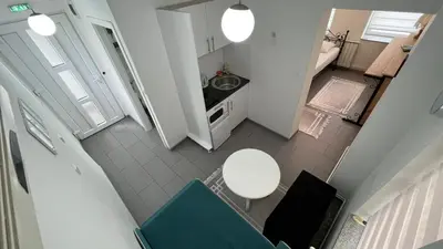 a small kitchen with a white table and a blue chair at Apartmani Aurora in Tuzla