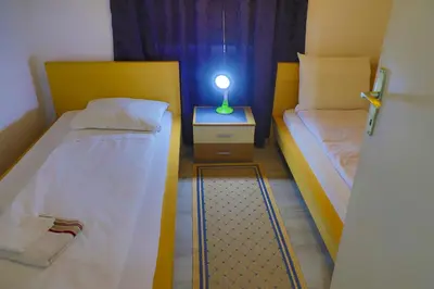 a small room with two beds and a lamp on a night stand at Apartman Bucko in Bihać