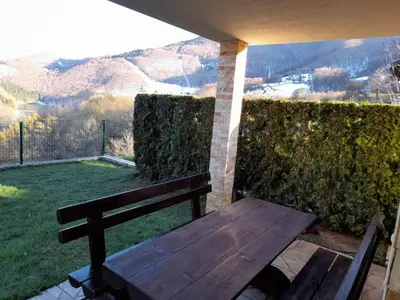 a wooden bench sitting on a patio with a view at Apartman Milekic in Mrkonjić Grad