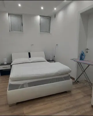 a white bedroom with a bed and a table at Apartman Dona in Banja Luka