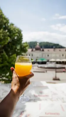 a person holding up a glass of orange juice at Fontana apartmani 1 FREE parking in Tuzla