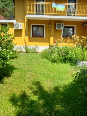 a yellow house with a balcony and a yard at Soba Dujaković in Banja Vrućica