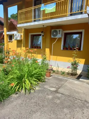 a yellow building with flowers and plants in front of it at Soba Dujaković in Banja Vrućica