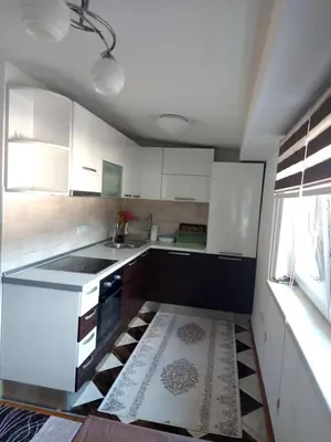 a kitchen with white cabinets and a black and white floor at Indy in Travnik