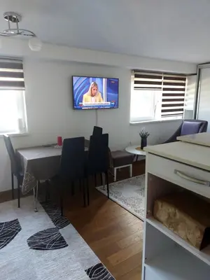 a living room with a table and a tv on the wall at Indy in Travnik