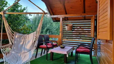 a porch with chairs and a table and a hammock at Holiday Home SAJRA in Kulen Vakuf