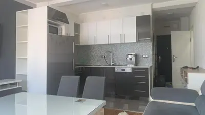a kitchen with white cabinets and a table and chairs at Stan na dan Banovići in Banovići