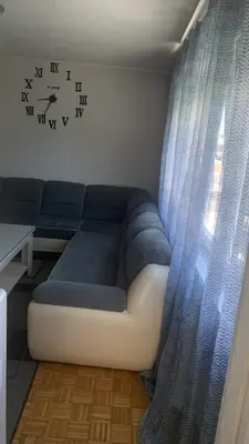 a couch in a room with a clock on the wall at Stan na dan Banovići in Banovići