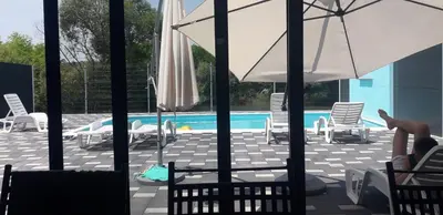a pool with chairs and umbrellas and a person sitting in avisoragement at 