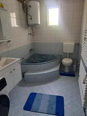 a bathroom with a tub and a toilet and a sink at Garden- pool apartman in Petrovice Donje